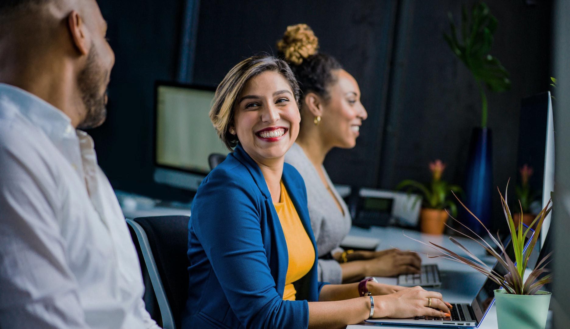 employees smiling and collaborating behind computers