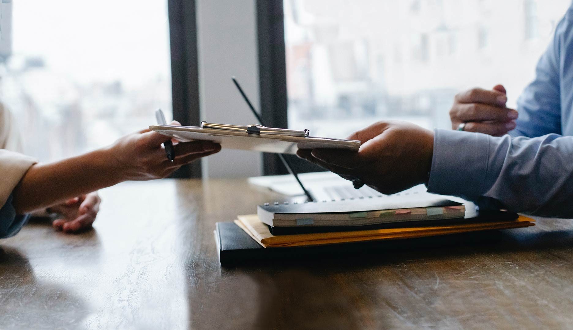 two persons hands transferring a document between each other